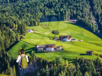 Warm autumn in the Val de Funes, Dolomites. Elderly woman - tourist with backpack travels in Tyrol. The concept of active and ecotourism