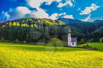 The concept of eco-tourism in Tirol. The famous church of St. Mary Magdalene and bell tower in a mountain valley. Dolomites, Tyrol, summer sunset