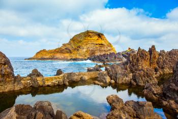  Volcanic island of Madeira. Rocks of the Atlantic coast. Small bay with smooth water on beautiful coast. The concept of exotic and ecological tourism