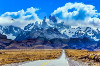 Summer day in Patagonia. Fine highway to the grandiose Mount Fitz Roy. The concept of active and extreme tourism. The Andean condors hover over the prairie