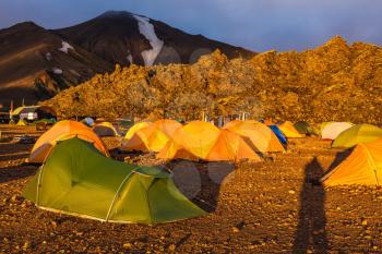 Fairy dawn National Park Landmannalaugar, Iceland. Tents tourists, mountains and glaciers covered with warm orange light