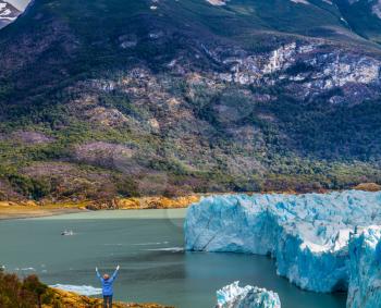 Woman -  tourist enthusiastically raised her hands. Patagonia. Unique lake and glacier Perito Moreno,  in a mountain valley. The concept of  exotic and extreme tourism