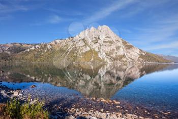 The mirror water of the lake reflects sharp peaks and rocks. Pyramidal mountain in the city of San Carlos de Bariloche. The concept of exotic and extreme tourism
