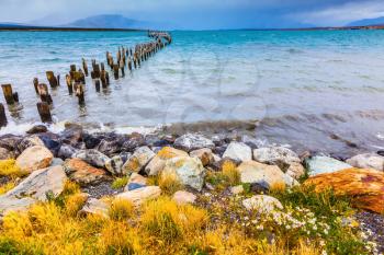 Strait of Magellan summer February afternoon. Waterfront, Punta Arenas. From the water stick piles of destroyed pier