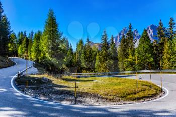 Dolomite Alps. Beautiful sunny day. The road passes in the coniferous forests at the foot of limestone and dolomite rocks. The concept of active, extreme and car tourism