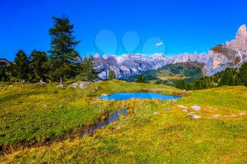 Southern Limestone Alps. The majestic white and gray rocks of the Italian Dolomites. Small puddle reflects the blue sky. The concept of active and car tourism