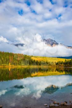 Patricia Lake amongst the forests, yellow bushes and mountains. Autumn in the Rocky Mountains of Canada