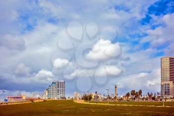 TEL AVIV, ISRAEL - JANUARY 1, 2016:  Strong winds and bright sunshine - perfect weather for a winter walk. Skyscrapers on Tel Aviv's seafront