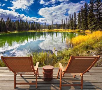  Two wooden deckchairs for tourists on ashore shallow round lake. Autumn day in Jasper  National Park in the Rocky Mountains of Canada