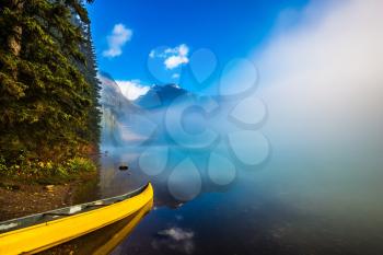 Misty autumn morning in the mountain Emerald Lake. Fishing boats moored on the shore. Canada, Yoho National Park