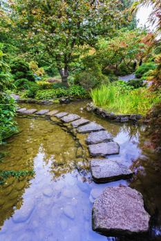   The track of stones in  water in Japanese part of garden. Decorative private garden on Vancouver Island in Canada - Butchart Gardens