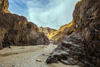 Israeli warm winter. Black canyon in ancient Eilat mountains. Orange and yellow sandstone warm glow in the sun