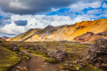 Travel to Iceland in July, volcanic summer tundra. Multi-colored rhyolite mountains - orange, yellow, green and blue
