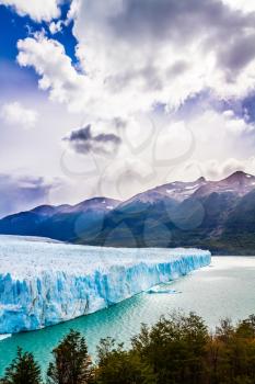 The fantastic glacier Perito Moreno, in the lake Argentine, Patagonia. The concept of exotic and extreme tourism. Clouds and glacier shine with reflected sunlight  



