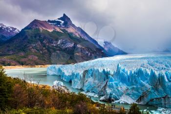 The colossal Glacier Perito Moreno in Patagonia on Lake Argentino. Argentine province of Santa Cruz. The cloudy sky covers the horizon. The concept of active and ecological tourism