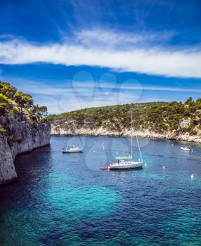  National Park Calanques on the Mediterranean coast. The picturesque narrow fjords between the rocky shore. White sailing boats waiting for tourists