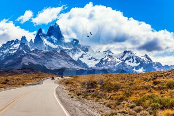 Argentine Patagonia. Summer day in February. Fine highway to the majestic Mount Fitz Roy. The concept of active and extreme tourism. The huge black Andean condors hover over the prairie