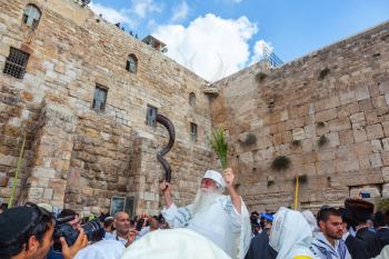 JERUSALEM, ISRAEL - OCTOBER 12, 2014: The area in front of Western Wall of  Temple filled with people. Elderly religious Jew with a Shofar. Morning autumn Sukkot
