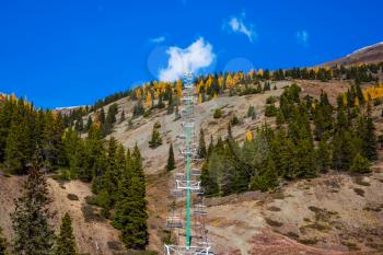 Suspended cable car over the wooded slopes of the mountains. Beautiful sunny autumn day. The Rockies of Canada. Concept of active and ecological tourism