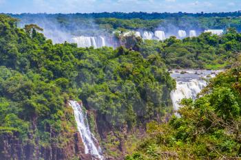 The fantastic roaring Iguazu Falls in South America, on the border of three countries: Brazil, Argentina and Paraguay. Concept of active and extreme tourism
