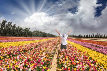 Flower kibbutz near Gaza Strip. Spring flowering buttercups. Stunned tourist in white shirt and bandana greets the rising sun