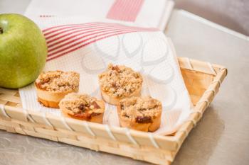  Magnificent portioned tartlet cakes with sweet stuffing. Professional baking. Background of wicker basket, white dish towel and green apple