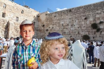 Cute little boy in a skullcap and his older brother seven years. They cost at Western Wall of Temple. The Jewish holiday of Sukkot