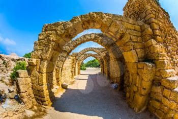  Excursion to the Archaeological Park of the Roman Empire. The remains of the covered arcades in ancient Caesarea. Sunny spring day. Israel. Concept of ecological and historical tourism
