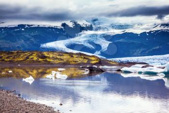 The colossal glacier Vatnajokull is melting at the edges, sliding to the ocean. Glacier meltwater form a picturesque lake. Summer in Iceland. The concept of extreme northern tourism