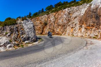 A lone motorcyclist on a steep turn of a mountain road  in the Provence. The fascinating journey to the canyon in Europe - Verdon. Concept of extreme and active tourism  