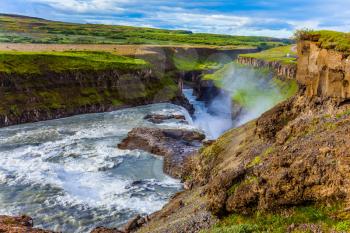  Summer day. Huge masses of water crash into the abyss. The most picturesque waterfall in Iceland - Gullfoss. The concept of extreme and phototourism