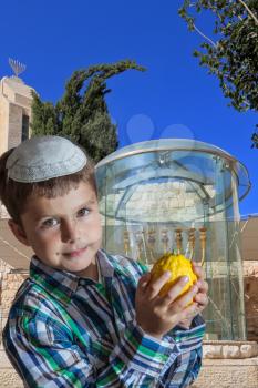 Cute seven year old boy in a white skullcap with the etrog. Sukkot at the Golden Menorah in Jerusalem