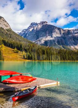Emerald Lake in the Canadian Rockies. Shiny red kayaks are dried upside down. The concept of active tourism and vacation