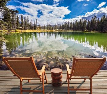 Two wooden deckchairs for tourists before round shallow lake. Autumn day in Jasper  National Park in the Rocky Mountains of Canada