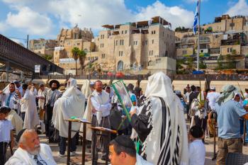JERUSALEM, ISRAEL - OCTOBER 12, 2014:  The area in front of Western Wall of Temple filled with people.  Morning autumn Sukkot, Blessing of the Kohanim. The Jews of tallit hold four ritual plants