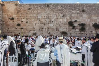 JERUSALEM, ISRAEL - OCTOBER 12, 2014:  Hhuge crowd of faithful Jews wearing white prayer shawls and black long-skirted coats. Morning autumn Sukkot