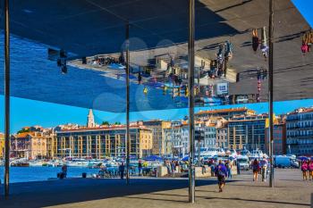 Marseille in May. The walking public are reflected in a mirror ceiling - canopy. Quay of the Old Port with giant mirror - shed 