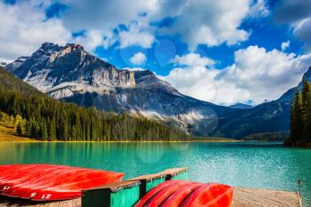 Shiny red kayaks are dried upside down. Emerald Lake in the Canadian Rockies. The concept of leisure and tourism