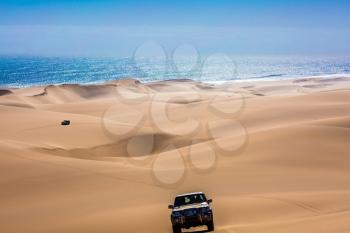  Fantastic jeep - safari through the huge sand dunes on the ocean shore. Atlantic coast of Namibia, south of Africa. The concept of exotic and extreme travel