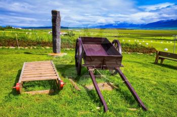 The reconstituted village - Pioneer Museum - Vikings in Iceland. Old wooden sledge and two-wheeled cart on the lawn