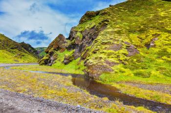 Picturesque basalt hills covered with green grass and moss. Streams from melting glaciers flowing down the canyon. Canyon Pakgil in Iceland