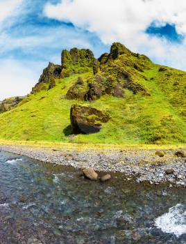 Pakgil Canyon - green grass and moss on the rocks. At the bottom of canyon flows small fast creek. Summer blooming Iceland