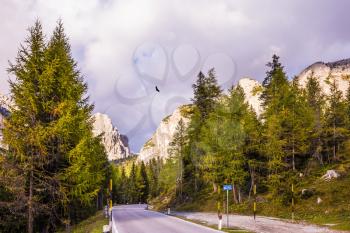 Concept of active and extreme tourism. The road in the Dolomites on the pass Faltsarego. Rocks covered the sunset rays