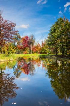 Shining day in French Canada. Concept of recreational tourism. Park fantastic beauty. Red and orange autumn foliage reflected in the clear water of the lake