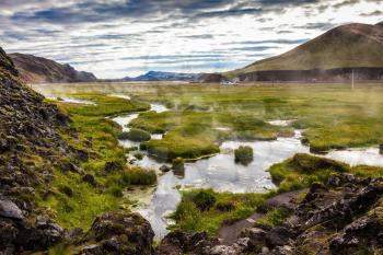 Hot steam over the source of the thermal waters. Sunrise Park Landmannalaugar. White nights in Iceland