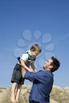 Royalty Free Photo of a Father Throwing His Child in the Air