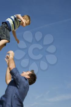 Royalty Free Photo of a Father Throwing His Son in the Air