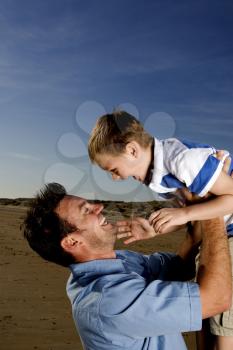 Royalty Free Photo of a Man Lifting His Child in the Air
