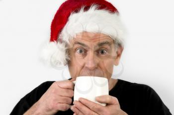 Royalty Free Photo of a Man in a Santa Hat Drinking Coffee