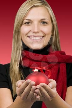 Royalty Free Photo of a Woman Holding a Red Ornament in the Palms of Her Hands